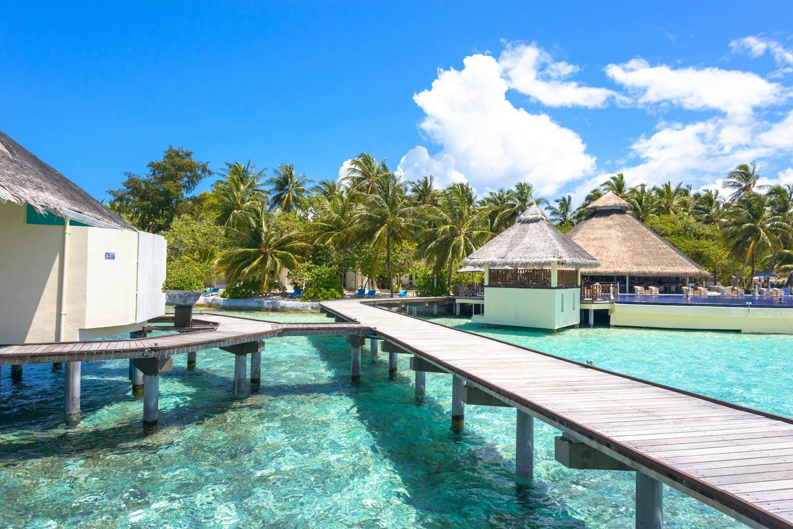 Overwater villas along a wooden jetty at sunset.